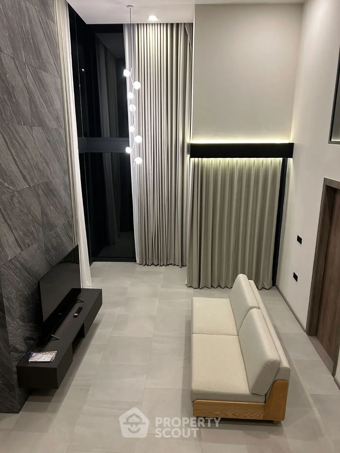 Modern living room with high ceilings, elegant lighting, and minimalist decor in a luxury apartment.