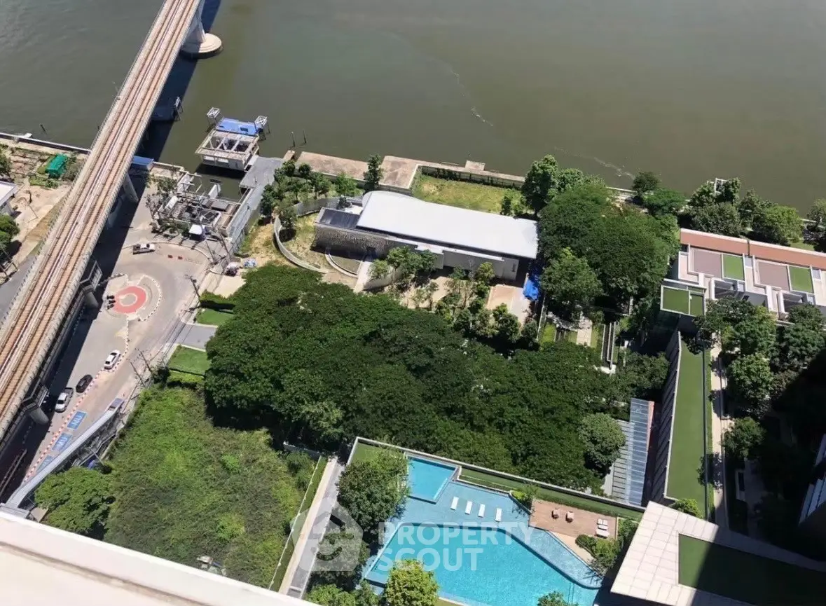 Stunning aerial view of riverside property with lush gardens and inviting pool area.
