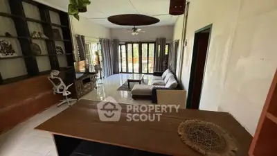 Spacious living room with modern decor and large windows offering natural light and garden view.