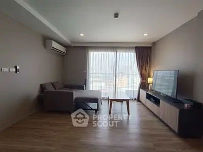 Modern living room with city view, featuring sleek furniture and large windows.