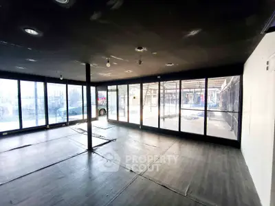 Spacious modern interior with floor-to-ceiling windows and sleek flooring, ideal for commercial use.