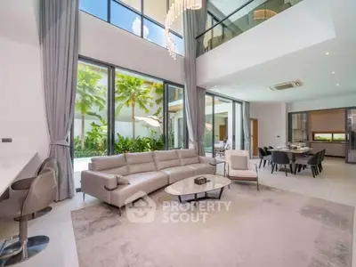 Luxurious open-plan living room with high ceilings and large windows overlooking a lush garden.