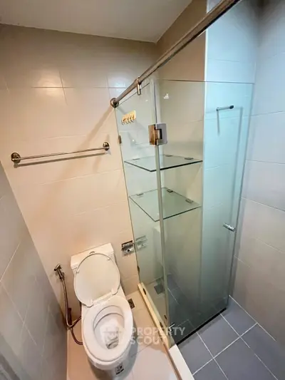 Modern bathroom with glass shower and sleek fixtures in a compact layout.