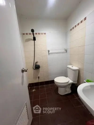 Compact bathroom with shower and toilet, featuring tiled walls and floor.