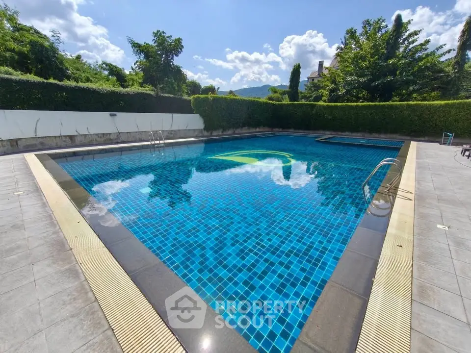 Luxurious outdoor swimming pool with clear blue water and lush greenery, perfect for relaxation.
