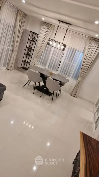 Elegant dining area with modern chandelier and floor-to-ceiling curtains in a spacious living room.