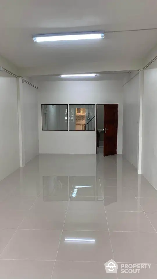 Spacious interior room with tiled flooring and glass partition, ideal for office or studio setup.