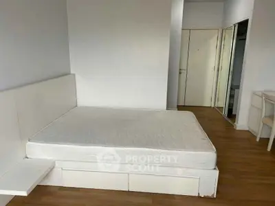 Spacious bedroom with minimalist design and wooden flooring, featuring a large bed and mirrored closet.