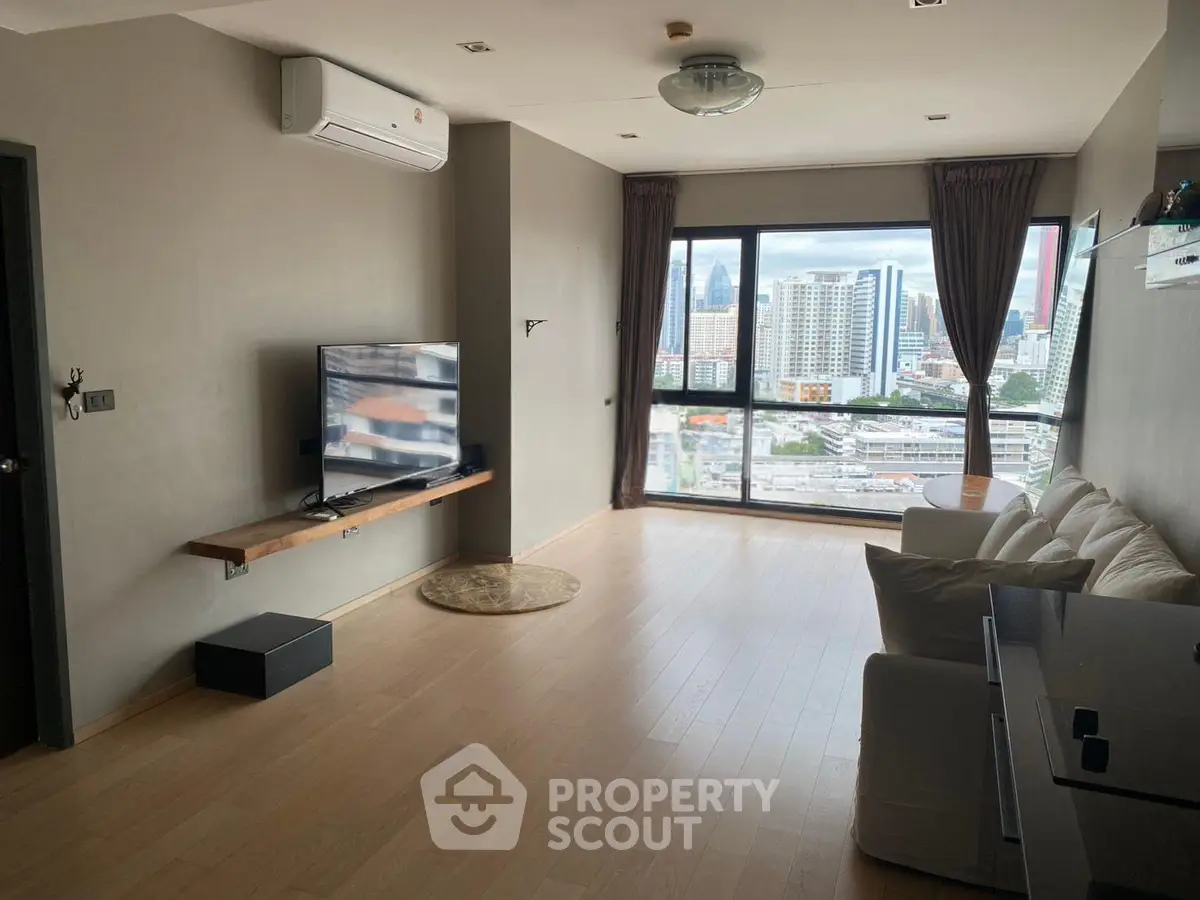 Spacious living room with city view, modern decor, and large windows in urban apartment.