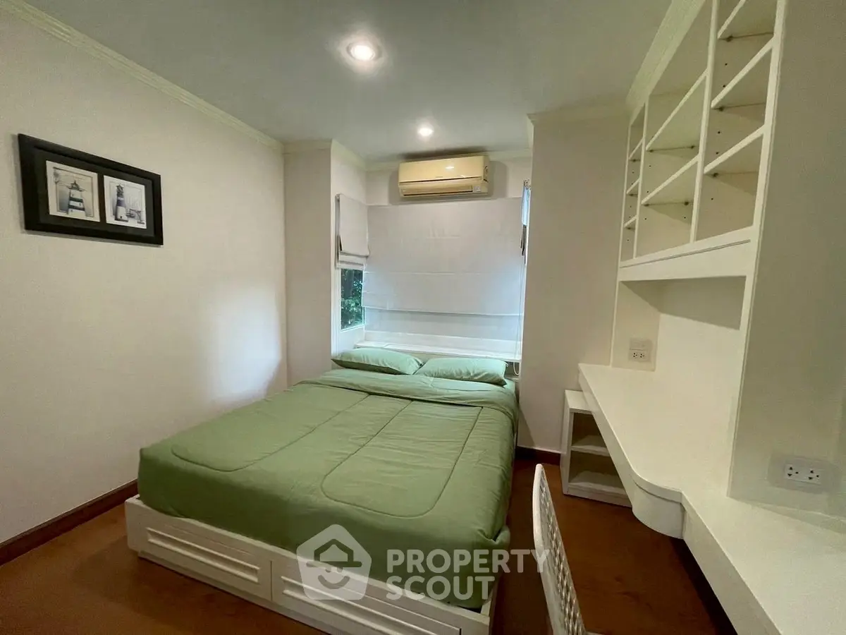 Cozy bedroom with green bedding and built-in desk, ideal for comfortable living.