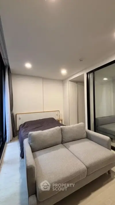 Modern bedroom with cozy gray sofa and stylish bed in a well-lit interior space.