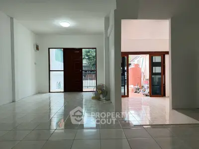 Spacious open-plan living area with tiled flooring and natural light.