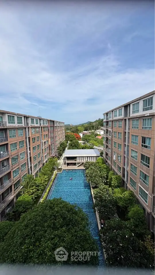 Stunning aerial view of modern apartment complex with lush greenery and inviting swimming pool.