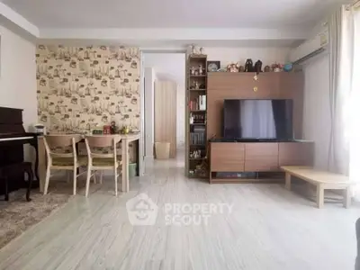 Spacious living room with modern decor and natural light, featuring a TV unit and dining area.