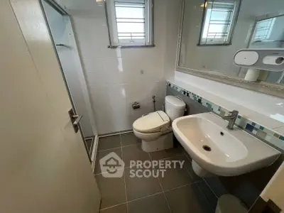 Modern bathroom with sleek fixtures and a large mirror, featuring a shower and toilet.