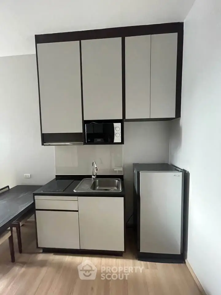 Modern compact kitchen with sleek cabinetry and mini fridge
