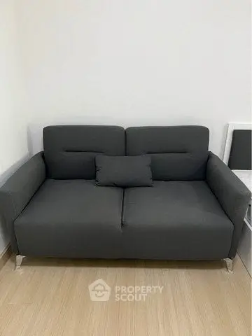 Modern gray sofa in a minimalist living room with wooden flooring.