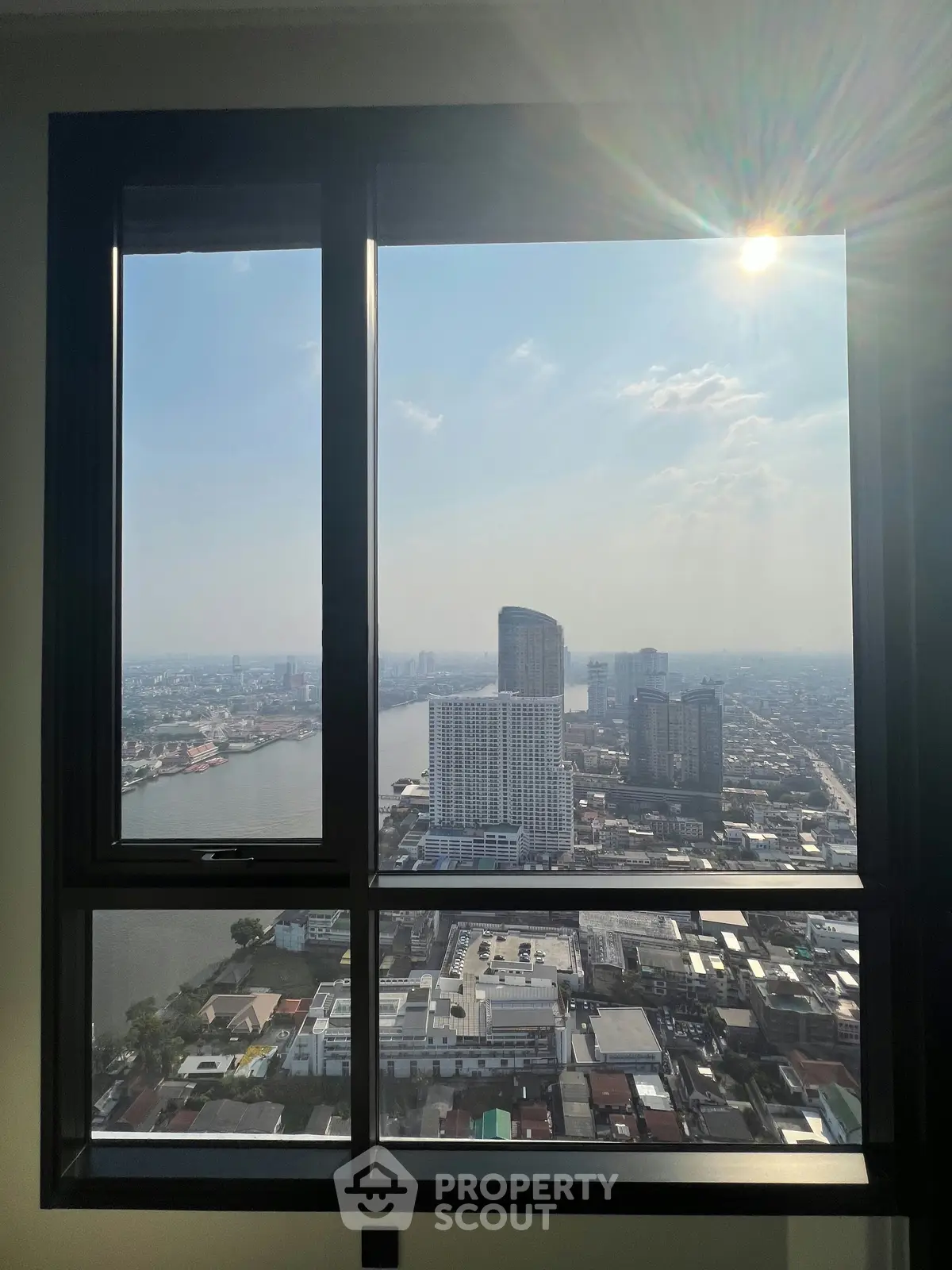 Stunning cityscape view from high-rise apartment window with river and skyline.