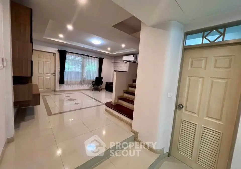 Spacious modern living area with elegant staircase and natural light.