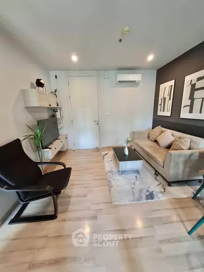 Modern living room with stylish decor, featuring a cozy sofa, sleek armchair, and wall-mounted TV.