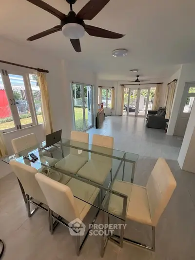 Spacious open-plan living and dining area with modern glass table and garden view.
