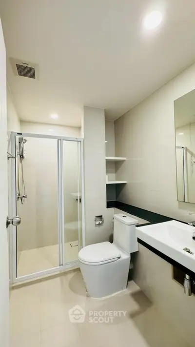 Modern bathroom with glass shower and sleek fixtures in a contemporary apartment.