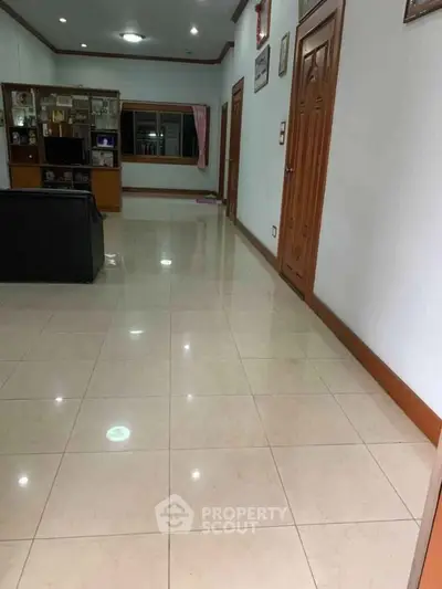 Spacious living room with tiled flooring and wooden accents, perfect for family gatherings.