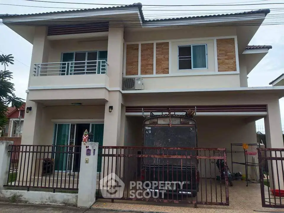 Modern two-story house with balcony and gated driveway