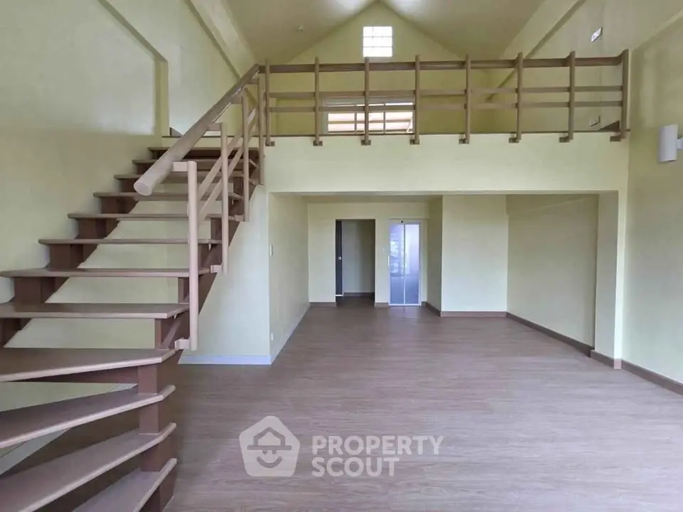 Spacious open-plan living area with mezzanine and wooden staircase, perfect for modern living.