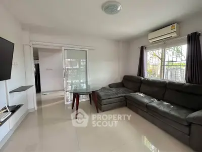 Spacious living room with modern sectional sofa and glass table, featuring air conditioning and natural light.