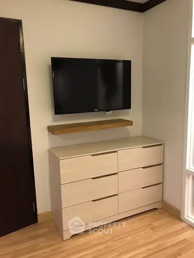 Modern bedroom with wall-mounted TV and sleek dresser
