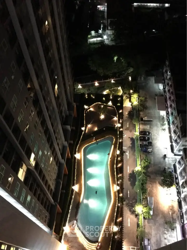 Stunning aerial view of illuminated pool in modern residential complex at night.