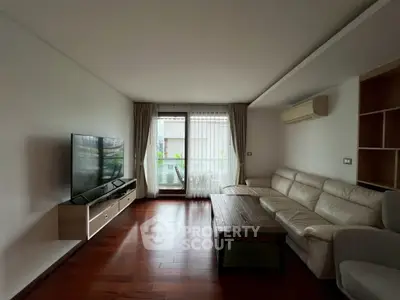 Spacious living room with modern furniture and large TV, featuring a balcony view.