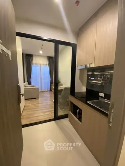 Modern kitchen with sleek cabinetry and open layout leading to cozy living room.