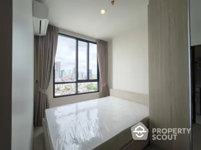 Modern bedroom with city view and large window in high-rise apartment