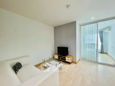 Modern living room with sleek furniture and glass sliding doors leading to a bright bedroom.