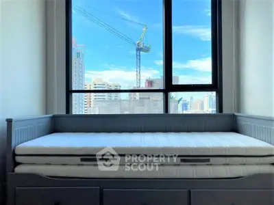 Bright bedroom with city view and daybed, ideal for urban living.
