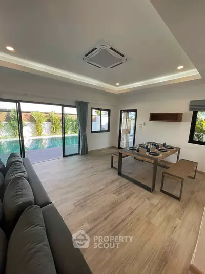 Spacious living room with pool view, modern decor, and elegant dining area.