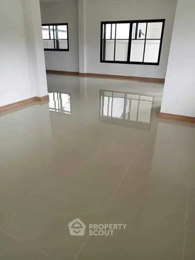 Spacious empty room with glossy tiled flooring and large windows, perfect for customization.