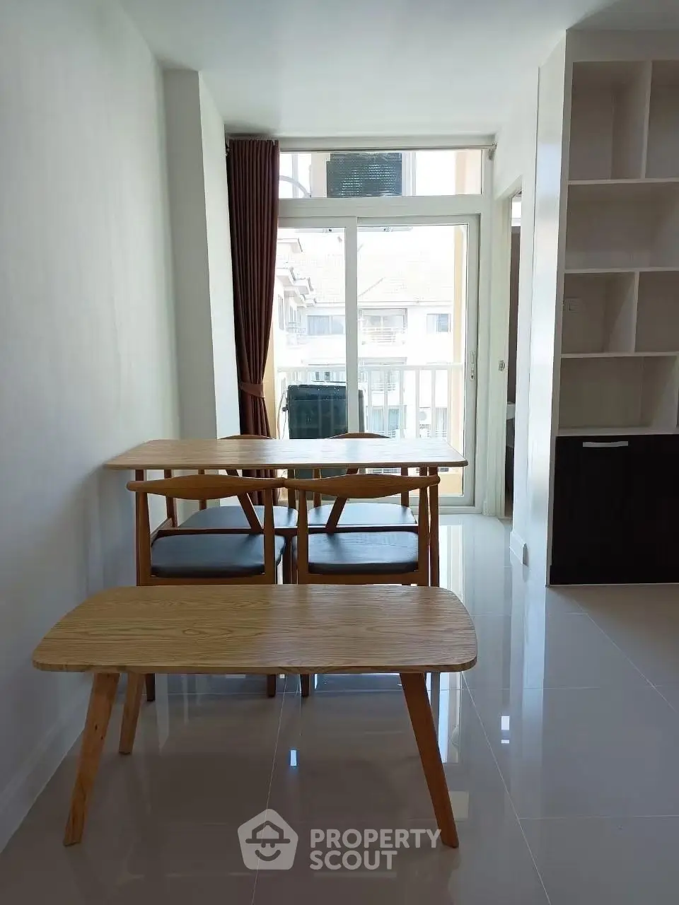 Bright dining area with modern wooden table and chairs, large window, and built-in shelving.