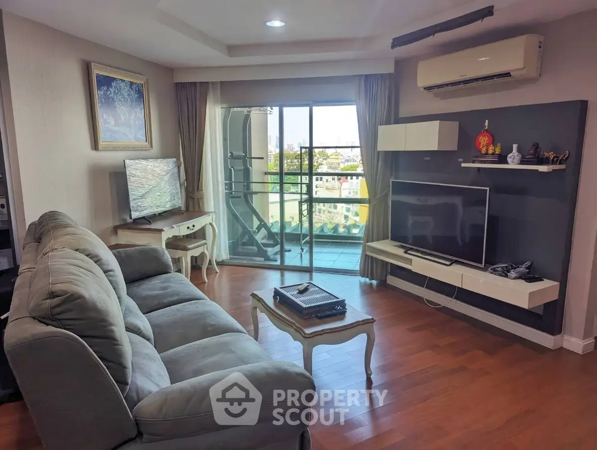 Spacious living room with modern decor and balcony view, featuring comfortable seating and entertainment setup.