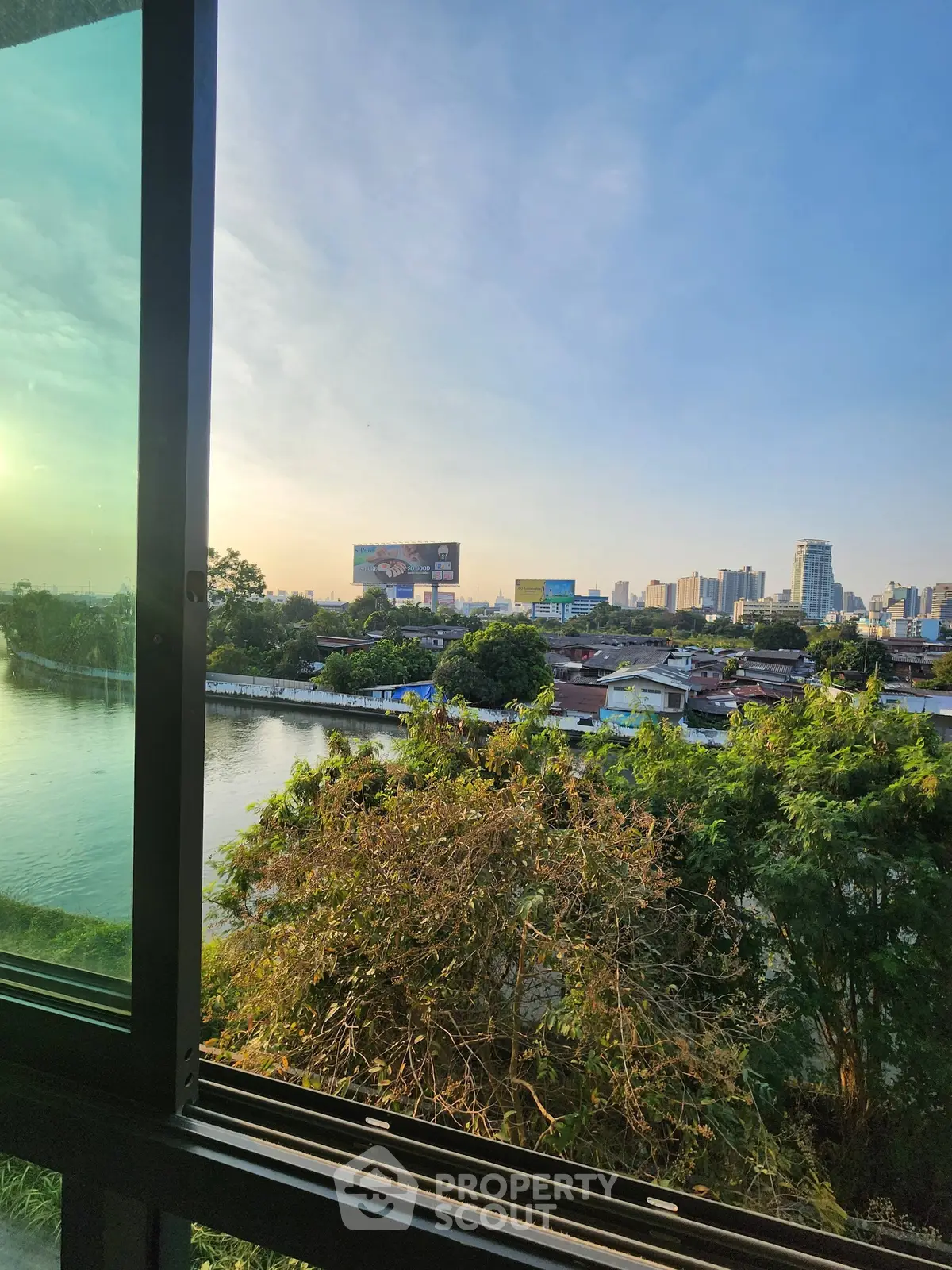 Stunning cityscape view from a window overlooking river and skyline, perfect for urban living.