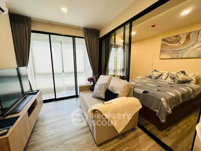 Modern studio apartment with cozy living area and stylish bedroom separated by glass partition.