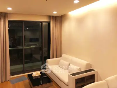 Cozy living room with modern sofa and glass door leading to balcony