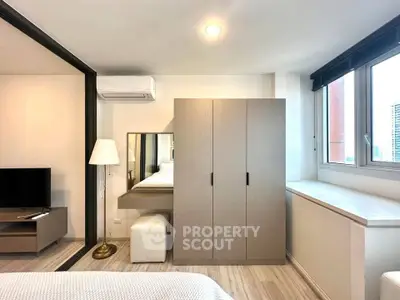 Modern bedroom with sleek wardrobe and large window offering city views.
