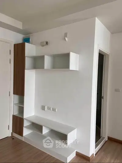 Modern minimalist living room with sleek white shelving and wooden accents.
