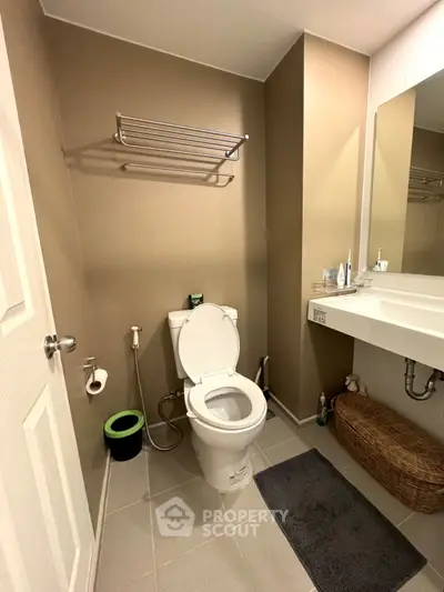 Modern bathroom with sleek fixtures and neutral tones, featuring a wall-mounted towel rack and spacious vanity.