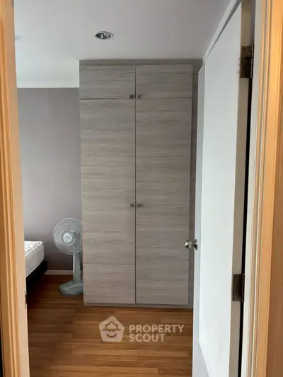 Modern bedroom with wooden flooring and built-in wardrobe, featuring a sleek design and cozy ambiance.