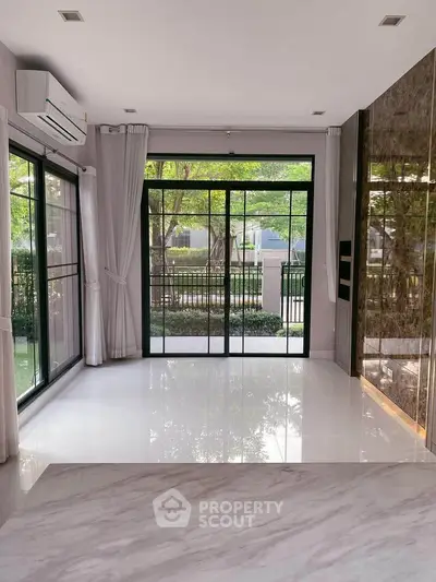 Spacious living room with large windows and garden view, featuring modern design and natural light.