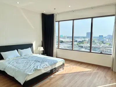 Spacious bedroom with large windows offering stunning city views